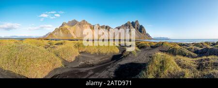 Epischer Blick auf den schwarzen Strand von Stokksnes an einem sonnigen Tag. Vestrahorn-Berg im Hintergrund. Natur- und Ökologiekonzept Hintergrund. Stockfoto