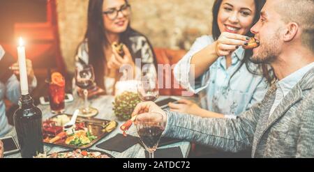 Eine Gruppe von Freunden, die in der amerikanischen Vintage-Bar Vorspeisen trinken - Junge Leute essen Fingerfood und trinken tropische Obstcocktails - Nachtleben, teilweise Stockfoto