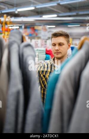 Junger Mann die Wahl Bademantel in Bettwäsche store Stockfoto