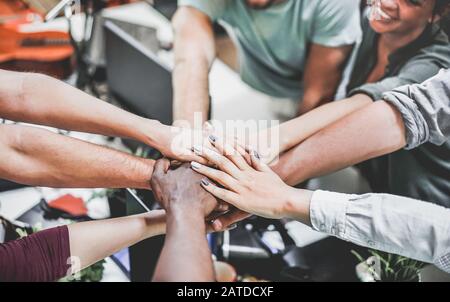 Junges Arbeitsteam feiert Neugründung im Kreativbüro - Glückliche Studenten geben Motivation - Fokus auf der Hand - Zusammenarbeit, Business, Stockfoto