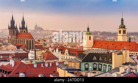 Prager Rotdächer und Türme der historischen Prager Altstadt. Das Stadtbild von Prag bei einem frostigen Sonnenuntergang. Rote Dächer, Türme und Prager Burg in der BA Stockfoto