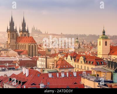Prager Rotdächer und Türme der historischen Prager Altstadt. Das Stadtbild von Prag bei einem frostigen Sonnenuntergang. Rote Dächer, Türme und Prager Burg in der BA Stockfoto