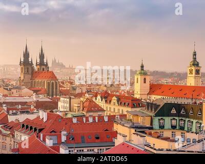 Prager Rotdächer und Türme der historischen Prager Altstadt. Das Stadtbild von Prag bei einem frostigen Sonnenuntergang. Rote Dächer, Türme und Prager Burg in der BA Stockfoto