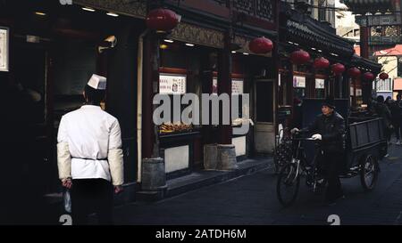 Peking, China - 26. Dezember 2018: Ein Koch vor seinem Lebensmittelstand in der Wangfujing-Straße, der geschäftigsten Handelsstraße Pekings, und beliebter Imbiss Stockfoto