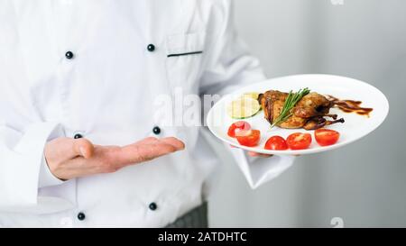 Unerkennbarer Chef-Halteplatte Mit Geröstetem Huhn In Der Küche Stockfoto