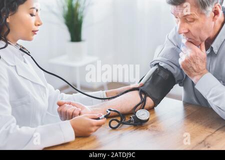 Ärztin, die Überprüfung der Blutdruck des älteren Menschen Stockfoto