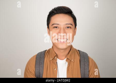 Portrait von Stattlichen asiatische Student mit Rucksack auf weißem Hintergrund Stockfoto