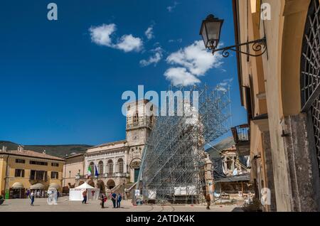 Palazzo Comunale, beschädigt, und Fassade, unterstützt von Gerüsten, der Basilika San Benedetto, die von Erdbeben zerstört wurde, in Norcia, Umbrien, Italien Stockfoto