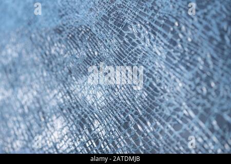 Zerbrochener Glashintergrund. Ein Glasfenster mit Kopfsteinpflaster gesprungen. Abstraktion. Mit einem kleinen Sonnenfass Stockfoto