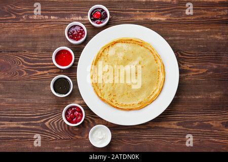 Draufsicht über dünne Pfannkuchen mit verschiedenen Marmeladen und Sauce Stockfoto