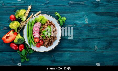 Linsen mit Rettich, Kirschtomaten, Bohnen und Gemüse. Gesunde Ernährung. Auf einem blauen Holztisch. Draufsicht. Freier Speicherplatz für Text. Stockfoto