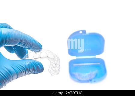 Hand, die transparente einzelne Zahnablage für Zähne hält, die vor dem blauen Zahnbehälter weiß werden Stockfoto