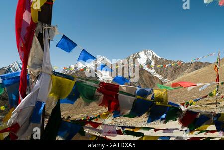 Schnee hat den Himalaya unter blauem Himmel und Gebetflaggen in den harten Wind im Sommer in der Nähe von Kaza, Himachal Pradesh, Indien, erreicht. Stockfoto