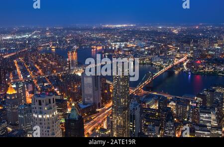 Die Brooklyn Bridge und die Skyline von Manhattan in New York City beleuchteten nachts mit einem Vollmond über dem Kopf. NYC Landscape Night Stockfoto