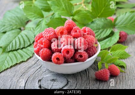 Himbeeren in Weiß Schüssel auf hölzernen Tisch Stockfoto