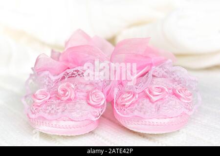 Pinkfarbene Babyschuhe auf weißer Häkeldecke. Stockfoto