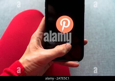 Junge Frau hält ein Smartphone mit Pinterest App auf dem Bildschirm. IPhone 11 mit einem Social-Media-App-Logo für interessante und außergewöhnliche Inhalte. Stockfoto