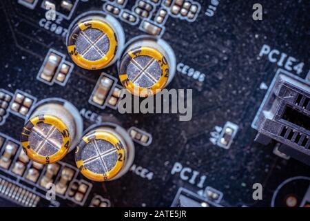 Gelbe Kondensatoren auf der dunklen PC-Hauptplatine schließen Stockfoto