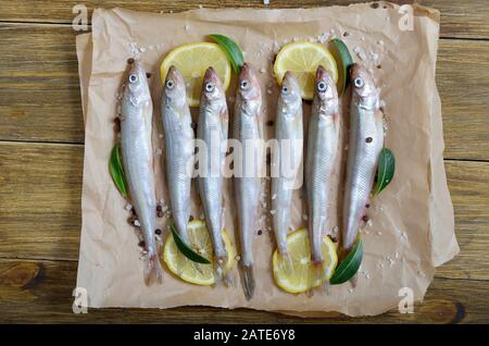 Frischer Fisch mit Gewürzen auf Papier. Draufsicht, flacher Lay Stockfoto