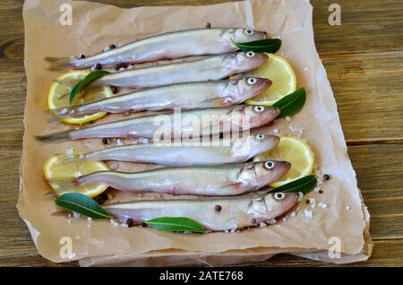 Frischer Fisch mit Gewürzen auf Papier Stockfoto