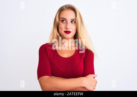 Junge schöne Frau, die rotes T-Shirt trägt, das über einem isolierten weißen Hintergrund steht und lächelt nach der Seite und starrt weg zu denken. Stockfoto