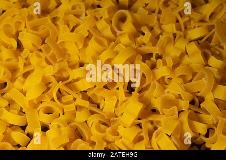 Pasta in Form von Buchstaben des englischen Alphabets und Zahlen. Nahaufnahme. Ansicht von oben. Kreativer Vintage-Hintergrund Stockfoto