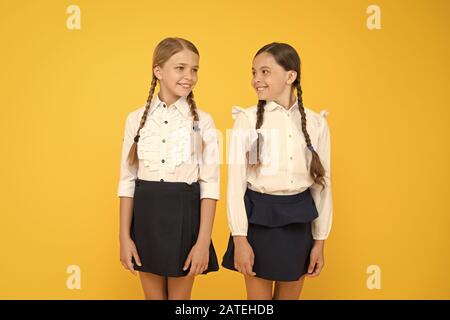 Freundliche Schüler. kleinen Mädchen auf gelben Hintergrund. Freundschaft und Schwesternschaft. beste Freunde. Kid formale Art und Weise. Ausbildung im Ausland. smart suchen Kinder. Schule Freunde. glückliche Kinder in Uniform. Stockfoto