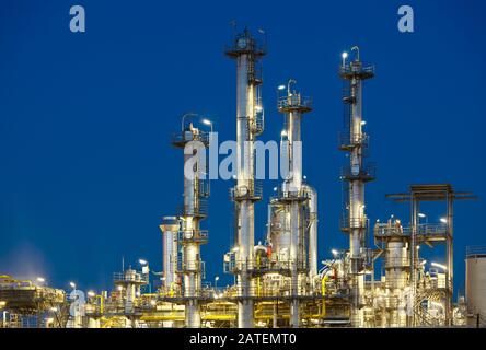Beleuchtete Destillationstürme einer Raffinerie mit perfektem nächtlichen blauen Himmel. Stockfoto