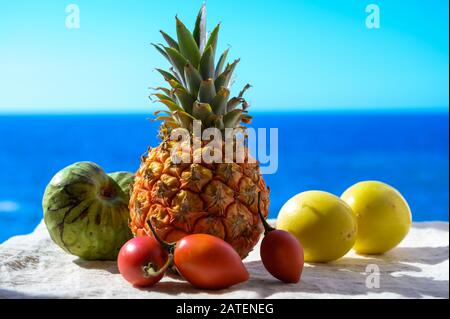 Tropische Früchte Sammlung, Custard Apple oder Grün reif cherymoia, Maracuja, Ananas, Mango, tamarillo Exotische Früchte auf blaues Meer Hintergrund in Stockfoto