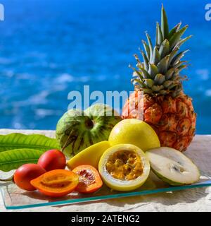 Tropische Früchte Sammlung, Custard Apple oder Grün reif cherymoia, Maracuja, Ananas, Mango, tamarillo Exotische Früchte auf blaues Meer Hintergrund in Stockfoto