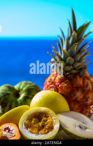 Tropische Früchte Sammlung, Custard Apple oder Grün reif cherymoia, Maracuja, Ananas, Mango, tamarillo Exotische Früchte auf blaues Meer Hintergrund in Stockfoto
