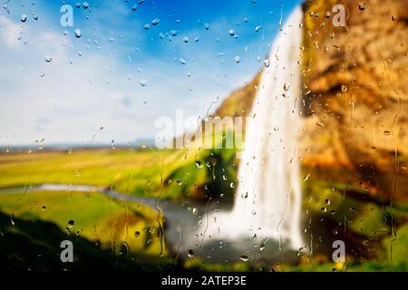 Blick auf einen Wasserfall durch ein Fenster mit Regentropfen. Stockfoto