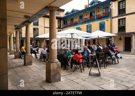 Personen in einer Restaurantterrasse mit Sonnenschirmen auf der Plaza El Fontán, einem traditionellen Straßenmarkt (Oviedo Innenstadt, Asturien, Spanien) Stockfoto