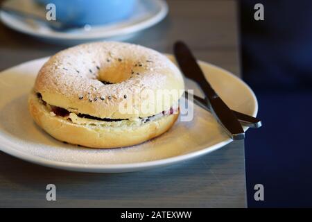 Frühstücksbagel mit Belägen und Kaffee auf dem Tisch Stockfoto