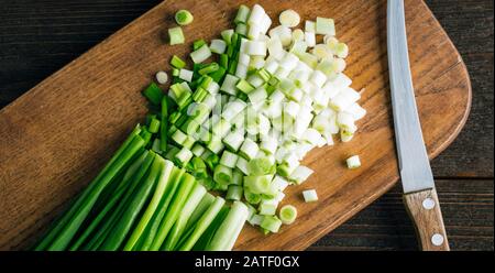 In Scheiben geschnittene Frische grüne Zwiebeln auf einem Holzschneidebrett Stockfoto