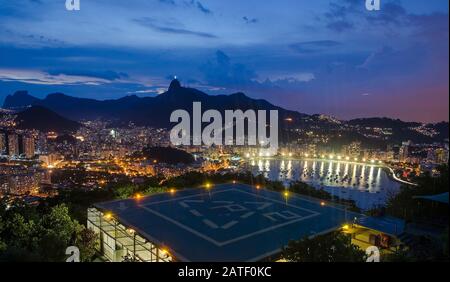 Nachtansicht von Botafogo in Rio de Janeiro. Hubschrauberlandeplatz auf dem Gipfel des Berges. Stockfoto