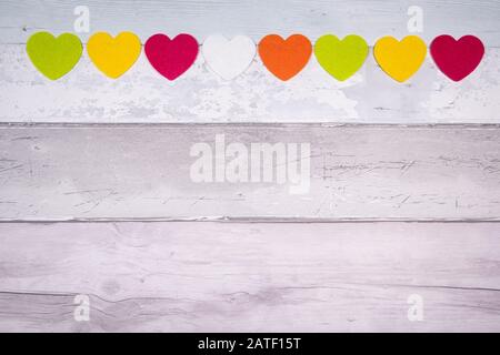 Bunte Filz Herzen auf dem Hintergrund der alten hölzernen Planken ähnelt einem alten Parkettboden. Konzept der Valentinstag und die Liebe im Allgemeinen. Stockfoto