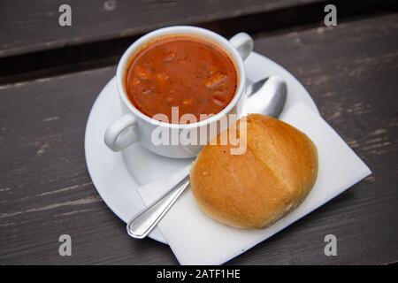 Soljanka mit Brötchen und Löffel auf einem Tisch Stockfoto