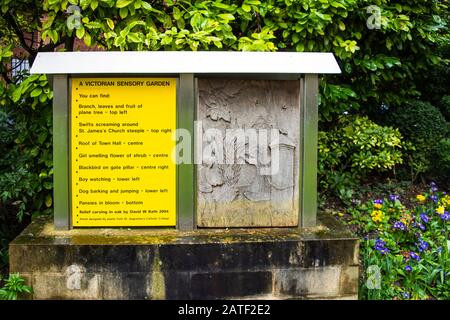 Eine geschnitzte taktile Anzeige mit schriftlicher und brailleer Beschreibung eines viktorianischen Gartens für die visuell in Trowbridge Stadt ausgekleideten Sinnesgarten Stockfoto