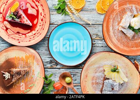 Auswahl an Frucht-Desserts und Backen auf einem Holztisch. Strudel, Cheesecake, Brownies, Eiscreme. Freier Speicherplatz für Ihren Text. Draufsicht. Stockfoto