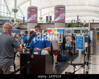 Der TSA-Agent führt den Mann durch den Sicherheitskontrollpunkt am Denver International Airport Stockfoto