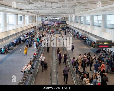 Piloten, Arbeiter und Passagiere in einem belebten Flughafenterminal mit beweglichen Gehwegen Stockfoto