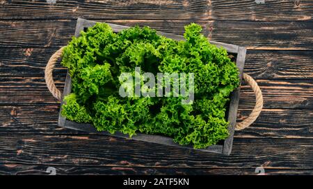 Grüner Salat in Holzkiste. Auf Holzgrund. Draufsicht. Kopierbereich. Stockfoto