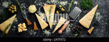 Satz harter Käse mit Käsemessern auf schwarzem Steingrund. Parmesan. Draufsicht. Freier Speicherplatz für Ihren Text. Stockfoto