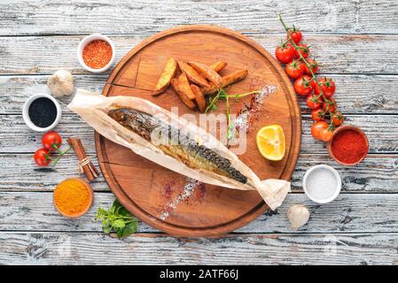 Gebackene Makrelenfische in Pergamentpapier. Auf einem Holzbrett. Freier Speicherplatz. Draufsicht. Stockfoto