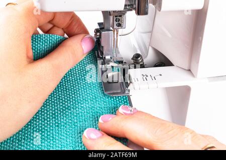 Pressfuß der Nähmaschine mit Nadel und Faden dicht oben. Detail Nähmaschine mit weiblichen Fingern. Frauen Nähen. Fertigungsstraße se Stockfoto