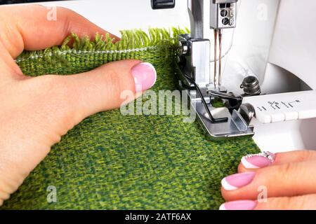 Pressfuß der Nähmaschine mit Nadel und Faden dicht oben. Detail Nähmaschine mit weiblichen Fingern. Frauen Nähen. Fertigungsstraße se Stockfoto