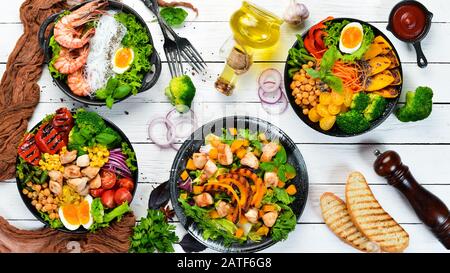 Buddha-Schüssel: Gemüse, Obst und Fleisch in schwarzem Teller auf altem Hintergrund. Herbstgerichte. Draufsicht. Freier Speicherplatz für Ihren Text. Stockfoto