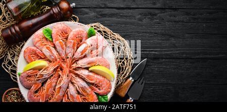 Große königliche Garnelen in einem Teller. Tigergarnelen. Draufsicht. Freier Speicherplatz für Ihren Text. Auf dem alten Hintergrund. Stockfoto