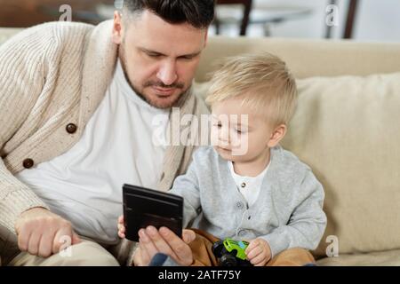 Junger Mann mit kleinen Jungen, der Gadget verwendet Stockfoto